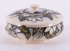 A Moorcroft dish with lid, decorated with white lilies and purple grapes, dated 2000.