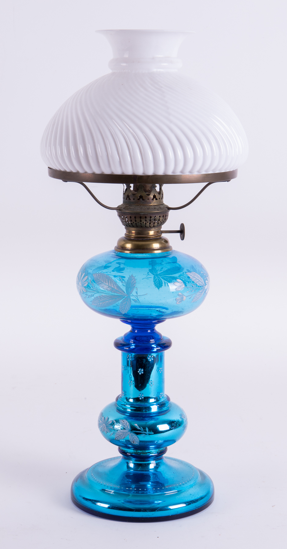 A blue glass oil lamp decorated with white flowers with a white shade, height 49cm.