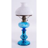 A blue glass oil lamp decorated with white flowers with a white shade, height 49cm.