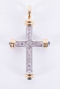 An 18ct white and yellow gold cross set with approx. 0.18 carats of round brilliant cut diamonds and
