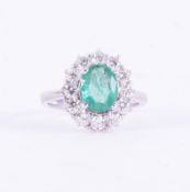 A cluster style ring set with a central oval cut emerald, approx. 1.50 carats, surrounded by round
