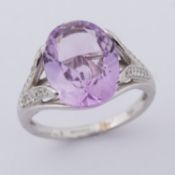 An 18ct white gold ring set with a central oval cut amethyst, approx. 4.20 carats, surrounded by