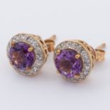 A pair of 9ct yellow gold stud earrings set with a round cut amethyst and surrounded by small