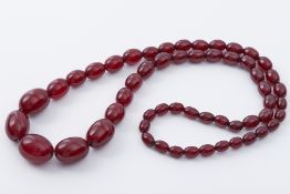 A string of oval cherry amber beads, approx 28", 66.4gm.