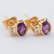 A pair of 18ct yellow gold stud earrings set with an oval cut amethyst with two small round cut
