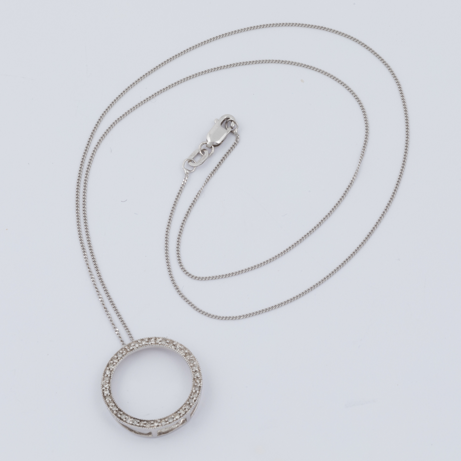 A 9ct white gold circle pendant set with small round cut diamonds, total diamond weight approx. 0.40