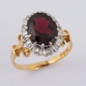 An 18ct yellow & white gold cluster ring set with a central oval cut garnet, approx. 2.90 carats,