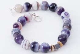 A necklace of banded agate beads with an off-set silver square cube bead & a sterling