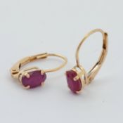 A pair of 9ct yellow gold earrings set with an oval cut ruby, total ruby weight approx. 0.74 carats,