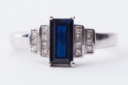 An 18ct white gold ring set with a central elongated rectangular dark blue sapphire,