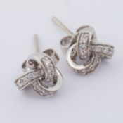 A pair of 9ct white gold knot design stud earrings set with small round brilliant cut diamonds, post