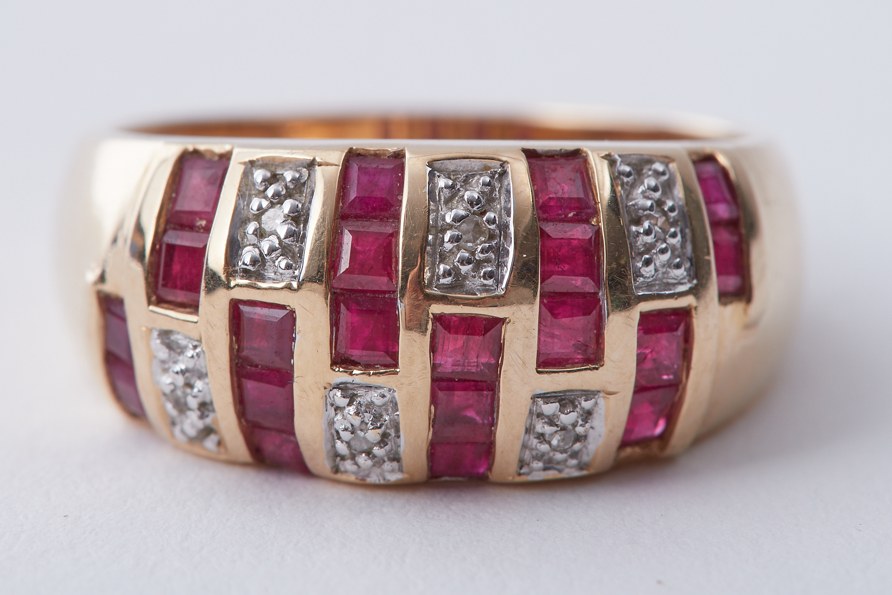 A 14k yellow gold ring set with square cut rubies and small round cut diamonds in an
