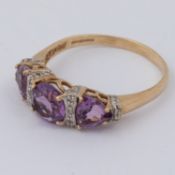 A 9ct yellow & white gold ring set with a central round cut amethyst with a triangular cut