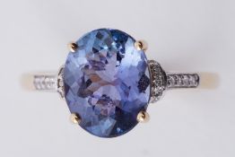 A 14k yellow & white gold ring set with a central oval cut AA Tanzanite, 3.56 carats with