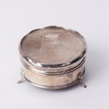 A circular trinket box on three feet with cartouche and monogrammed lid probably silver but no