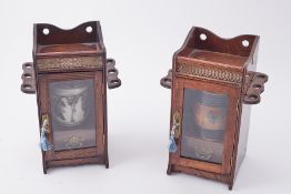 A pair of oak tobacco cabinets each containing a pottery tobacco jar including studio pottery jar