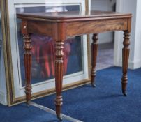 A 19th century mahogany fold over tea table on fluted legs with original brass casters.