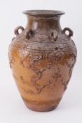 A large Oriental earthen ware jar, possibly Japanese, embossed with stylised dragons and six