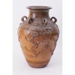 A large Oriental earthen ware jar, possibly Japanese, embossed with stylised dragons and six