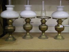 A group of 4 early 20th century brass oli lamps: with chimneys and shades (1 shade absent) (4).