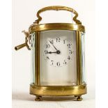 Oval brass cased carriage clock timepiece: Measures 15cm including handle. Winds, ticks, sets and