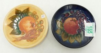 Two Moorcroft coasters decorated in the finch and berry design: one on blue, one on ochre (2)