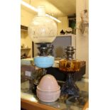 Two oil lamps together with a single chimney and 2 shades.