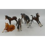 A collection of Beswick and Royal Doulton foals to include lying 915, grazing foal, large foal