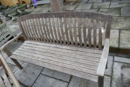 A teak garden bench having shaped back