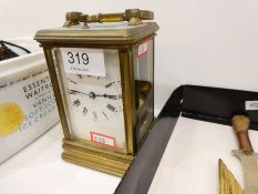 An old brass carriage clock having striking movement with enamelled dial