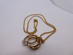 Unmarked yellow metal neck chain hung with 3 9ct yellow gold charms in the form of 3 rings, pendant