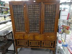 A modern Oriental style cupboard having three door with four drawers under, 130cm
