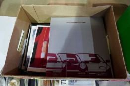 Box of car brochures including Audi, Porsche, Lotus, etc