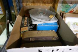 Shelf of mixed items to include paintings, records, brass cannons, box projector equipment