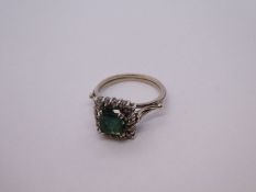 White metal, possibly 18ct white gold cluster ring with central cushion cut emerald surrounded diamo
