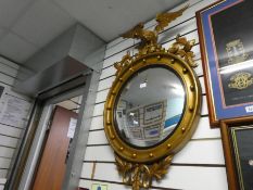 A gilt convex small mirror having eagle surmount, width 59cms