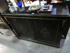 A Victorian ebonized two door cupboard having inlaid and gilt metal decoration