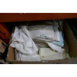 A box of vintage tablecloths, napkins with various embroidered designs and colours