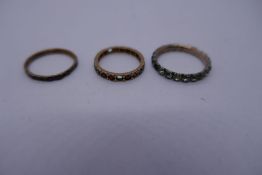 Ring box containing three eternity rings, all AF, one possibly gold with garnets