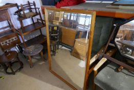 A bevelled glass wall mirror in pine frame