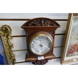 An early 20th century carved walnut aneroid barometer