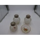 A quantity of silver topped, globe cut glass scent bottles with repousséd design lids AF. Worn. One