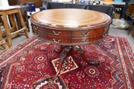 A reproduction drum style centre table having leather top, with two drawers on carved tripod base, 9