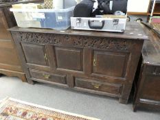 An antique oak mule chest having carved frieze with two cupboard doors and drawers below, 127cms