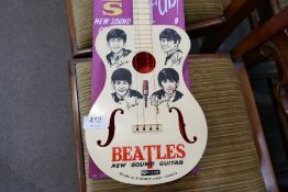A Selcol Beatles guitar on reproduction cardboard back (guitar length 58cms)