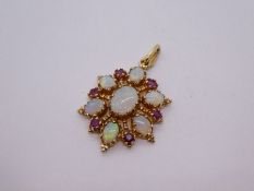 Victorian style yellow gold opal and ruby starburst pendant comprising central oval cabouchon light
