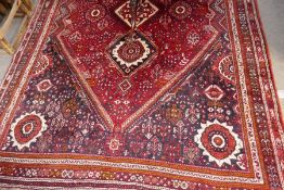 An Iraninan red ground carpet having three central diamond medallions with allover floral decoration