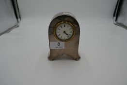 A nice looking silver desk clock standing on four ball feet. 13cm x 8cm approx. Nice shape with arch