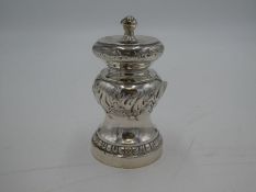 An ornate Victorian silver pepper mill with decorative chased design and central vacant cartouche. H