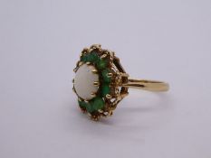 9ct yellow gold opal and emerald cluster ring with central circular light opal, surrounded by 11 eme